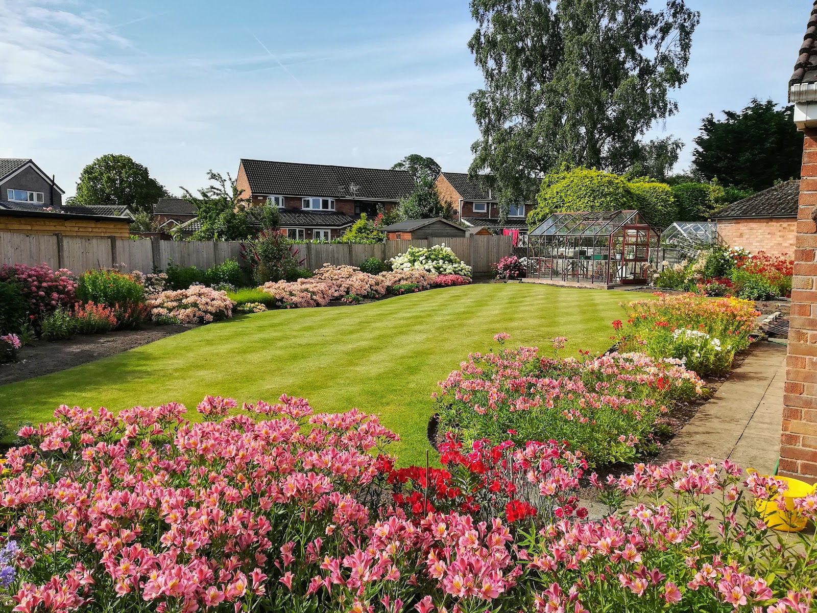 A striped, freshly mown lawn edged with vivid flower borders, kept by Parker's Gardens in Westhoughton