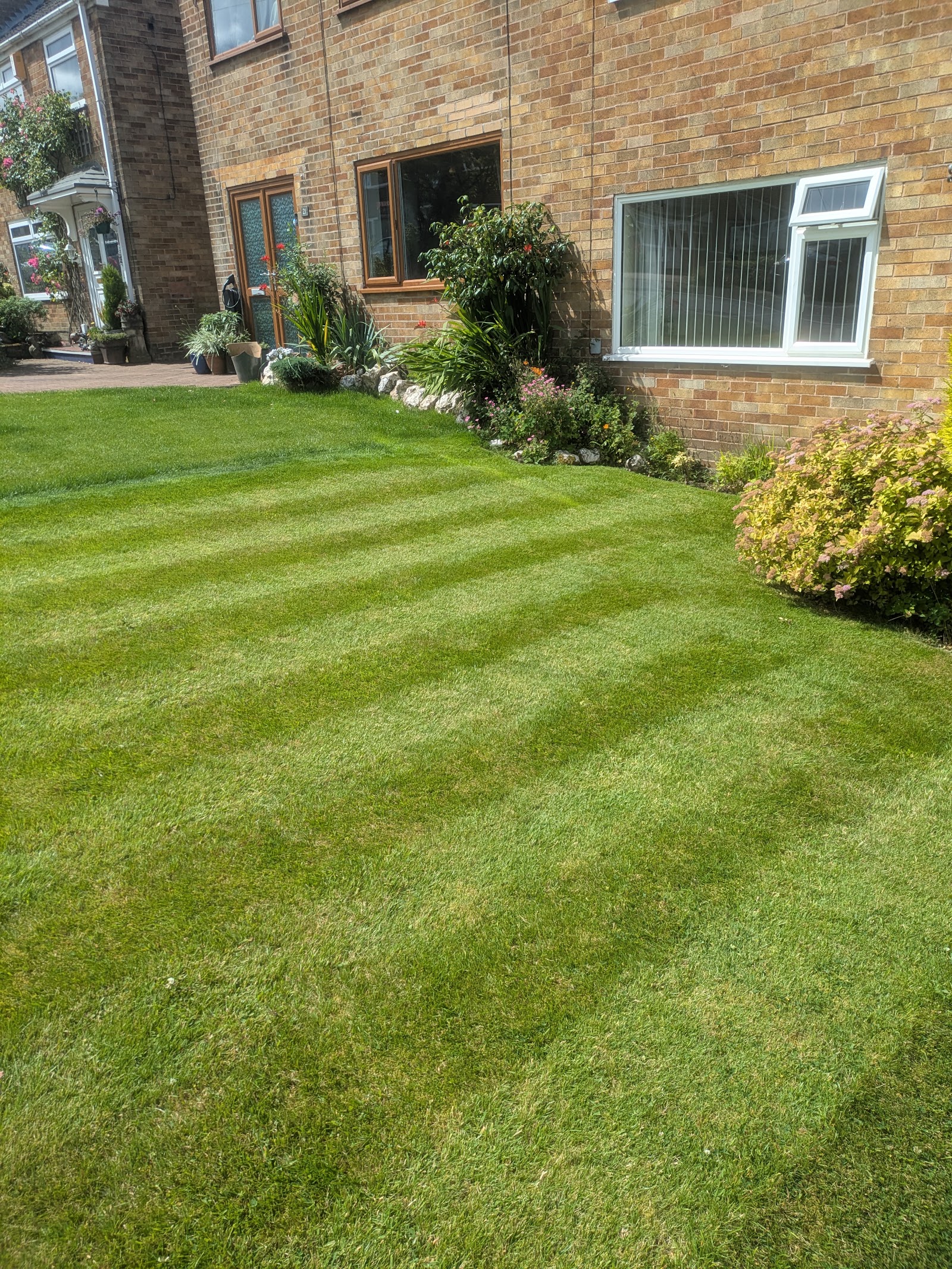A neat, striped front lawn running up to a brick house